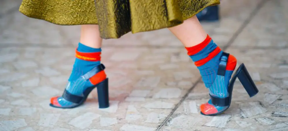 Gestreifte Socken in Blau und Rot zu Sandalen auf einem gemusterten Steinboden